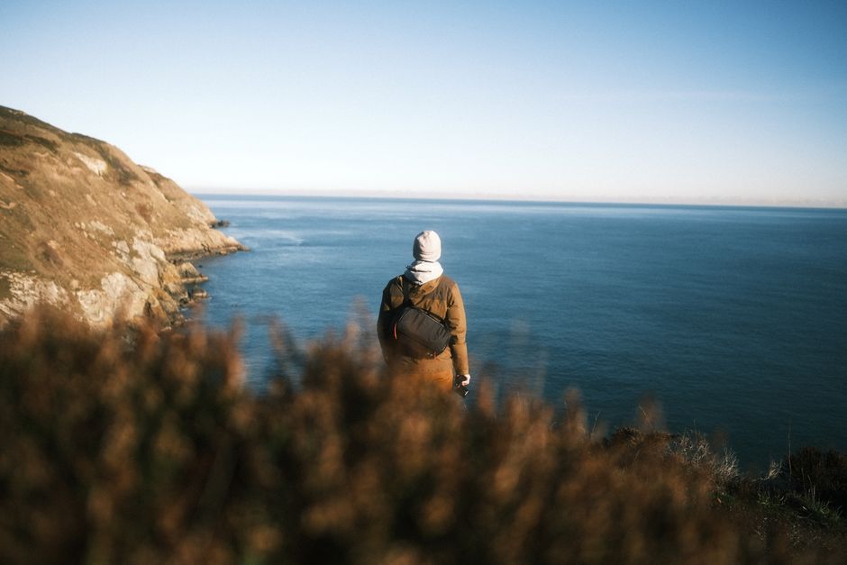 A lone traveler stands at a cliff edge, overlooking Dublin's stunning coastline.