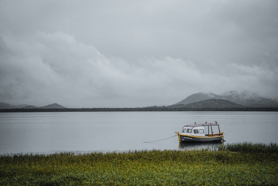 Serene image of a lone boat on a foggy lake with mountains in Antonina, Brazil.