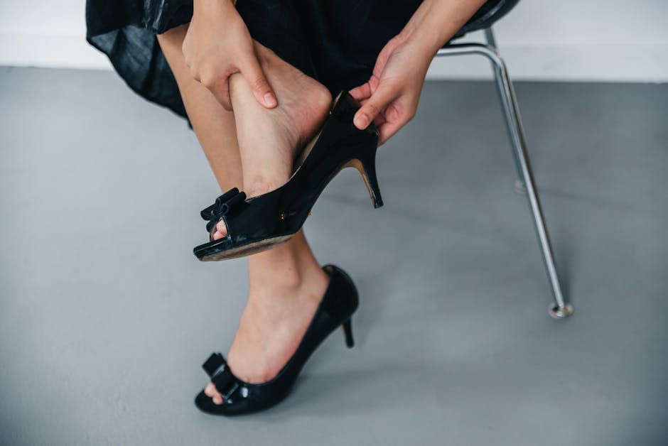Close-up of a woman removing black high heels while seated indoors.