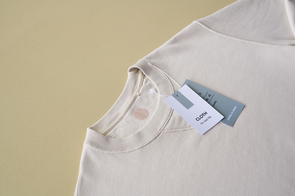 Minimalist beige sweatshirt displayed with tags on a yellow background, perfect for e-commerce.