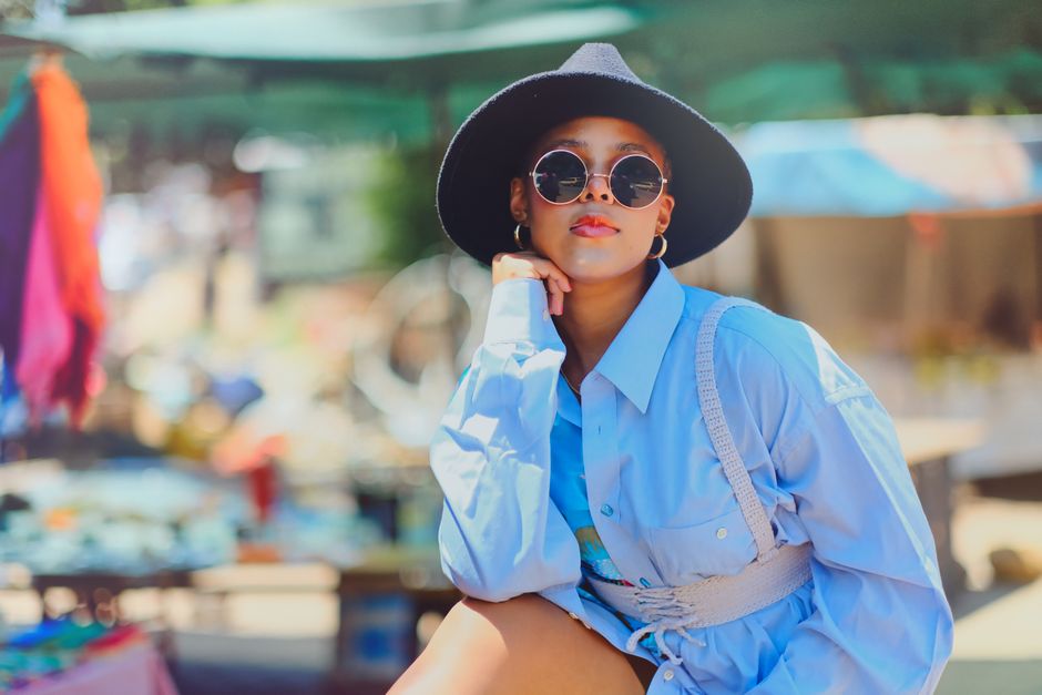 Trendy woman in stylish summer outfit and sunglasses at an outdoor market.