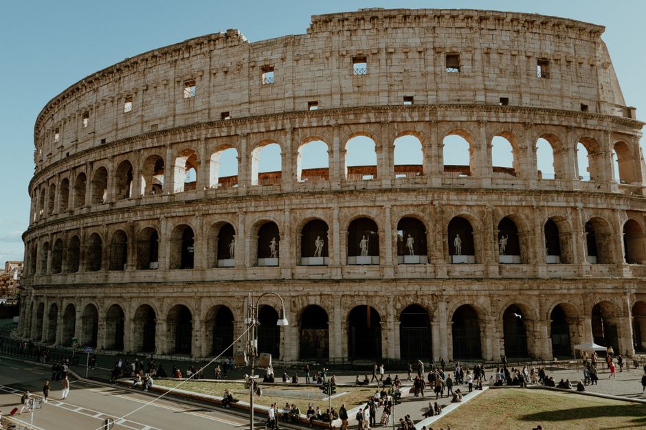 Iconic Colosseum in Rome captured on a sunny day with tourists exploring the ancient structure.