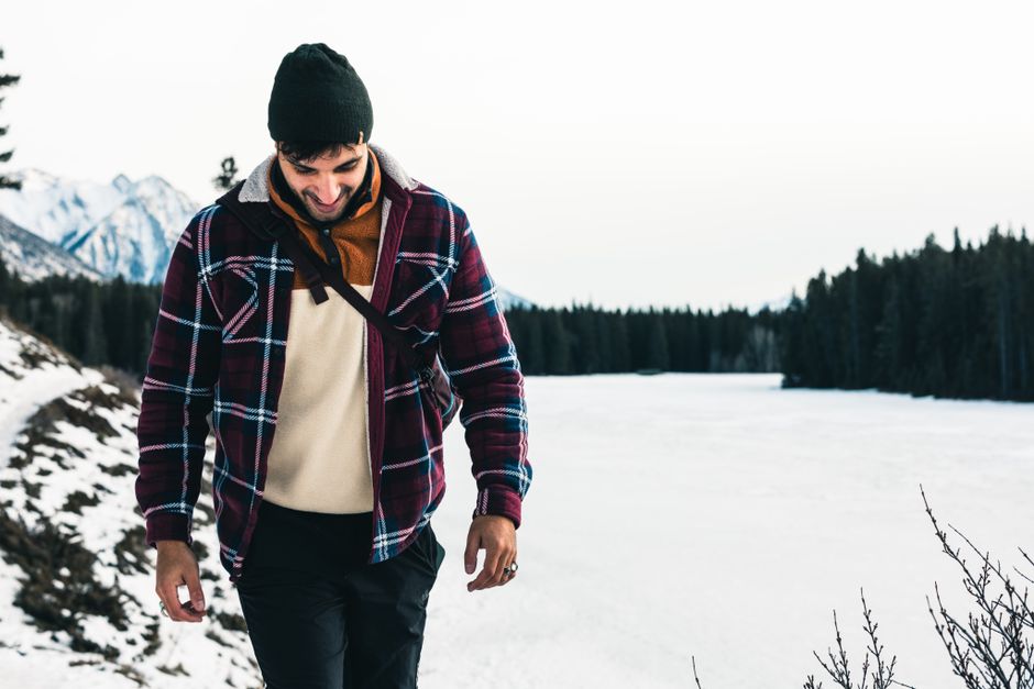A man enjoys winter hiking in Banff, Canada, surrounded by snowy mountains and a frozen lake.
