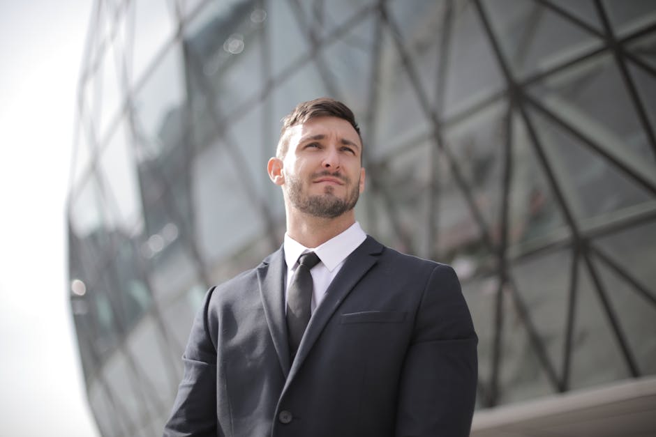 Portrait of a confident businessman in a suit standing outside a modern office building.