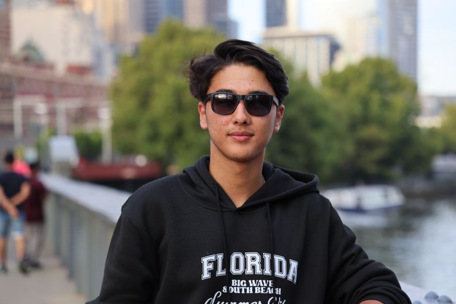 Casual portrait of a young man wearing sunglasses in a city setting with blurred background.