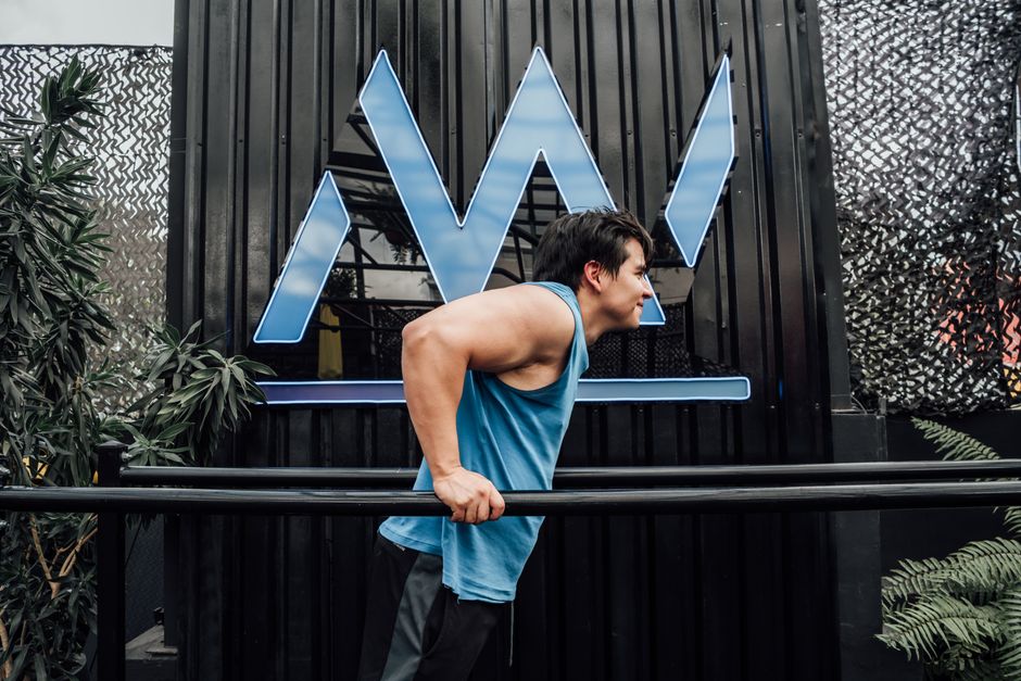 A muscular man working out on bars outdoors in Mexico City, showcasing strength and fitness.