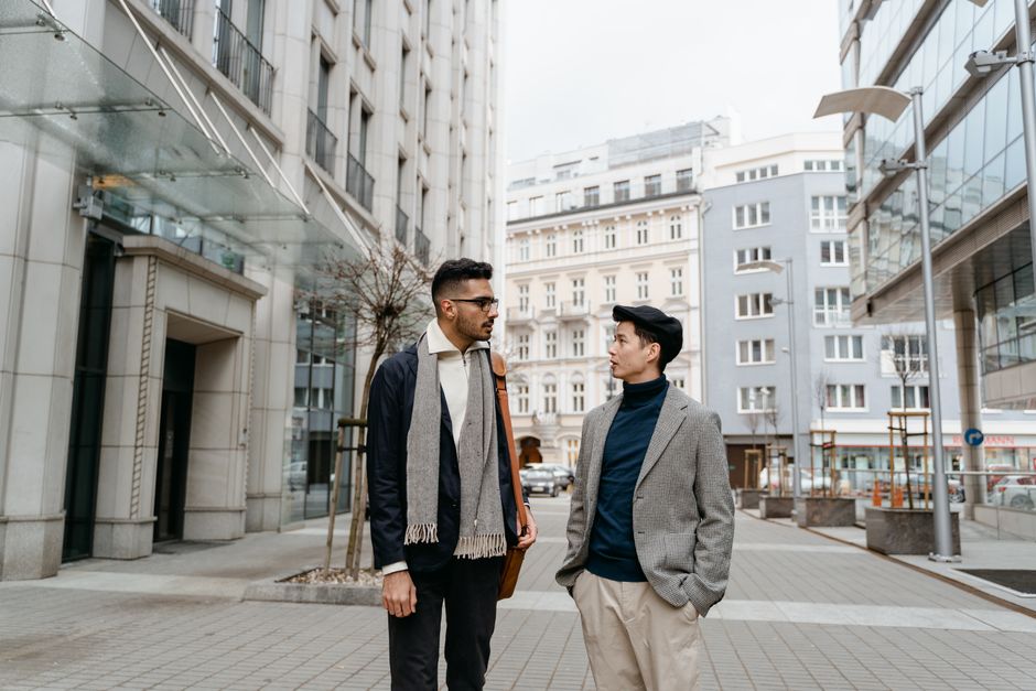 Two adults discussing amidst modern urban architecture on a city street.