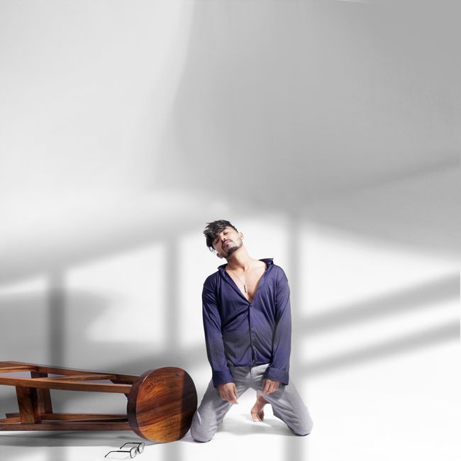 Young man posing dramatically with modern fashion against studio backdrop.