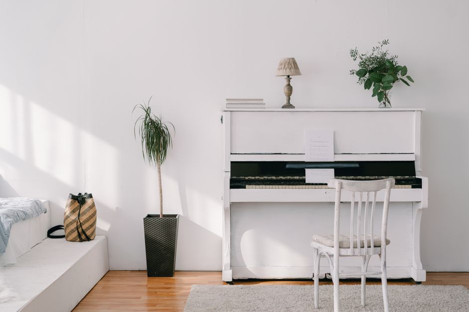 Elegant minimalist interior featuring a white upright piano, green plants, and natural light.