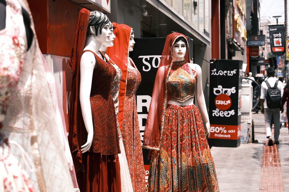 Vibrant mannequins showcasing traditional Indian lehenga outfits in Bengaluru's bustling market street.