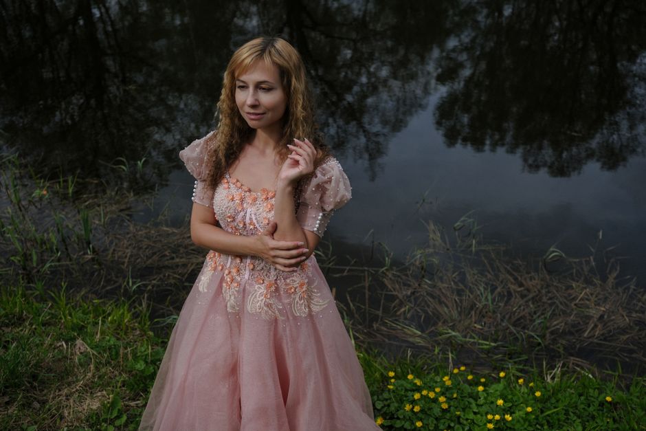 A serene portrait of a woman in a pink dress by the water, capturing natural beauty.
