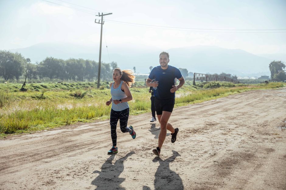 Group of joggers running along a rural dirt path surrounded by nature.
