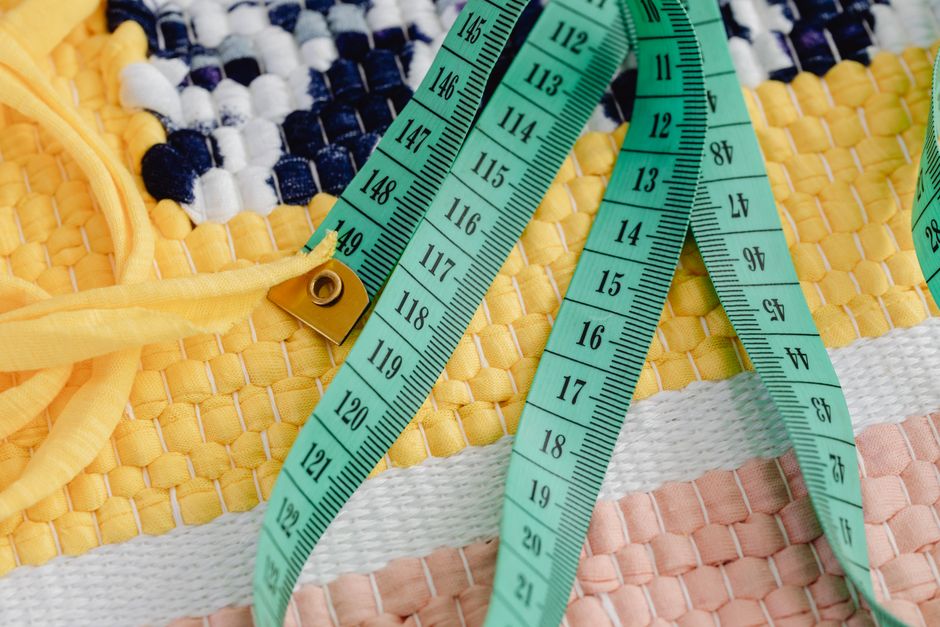 Close-up of a colorful woven textile with a green measuring tape. Perfect for crafting themes.