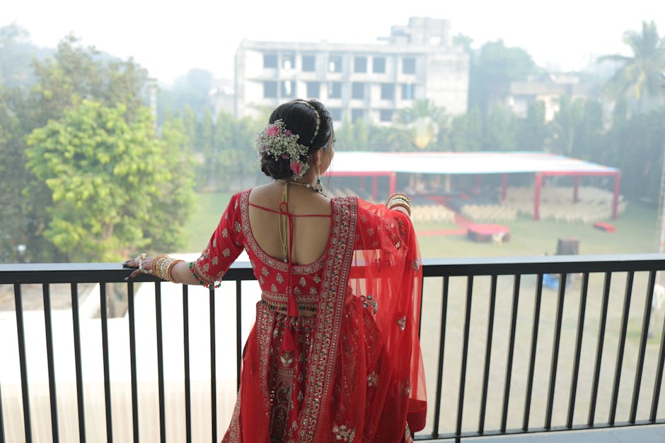 Back view of a bride in red traditional attire overlooking a garden venue.