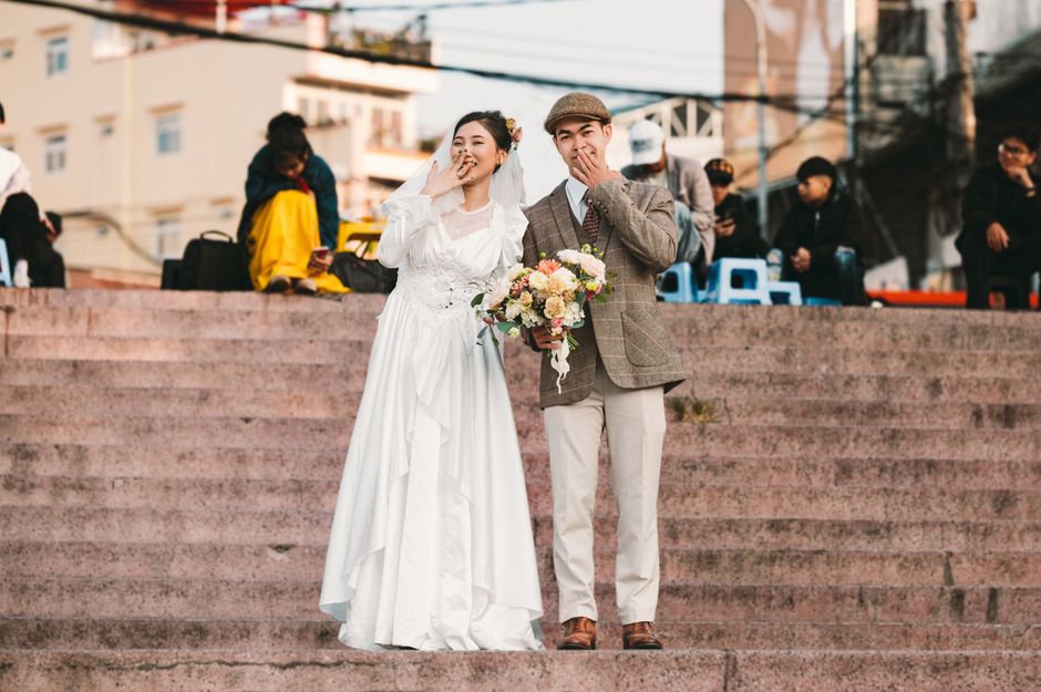 Bride and groom pose on stone steps outdoors, capturing a charming wedding moment.