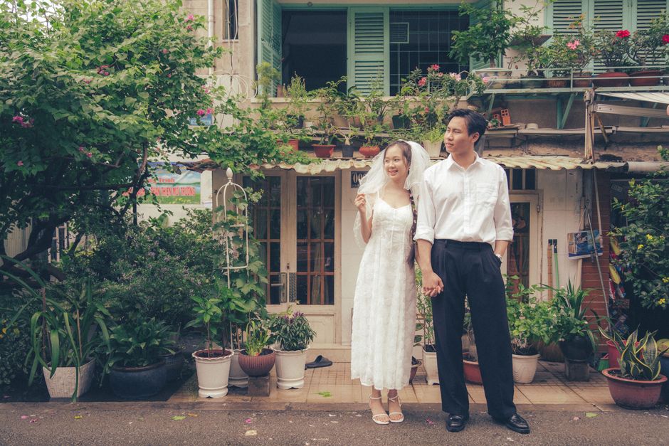 Joyful newlywed couple stands hand in hand in a lush garden, embodying love and happiness.