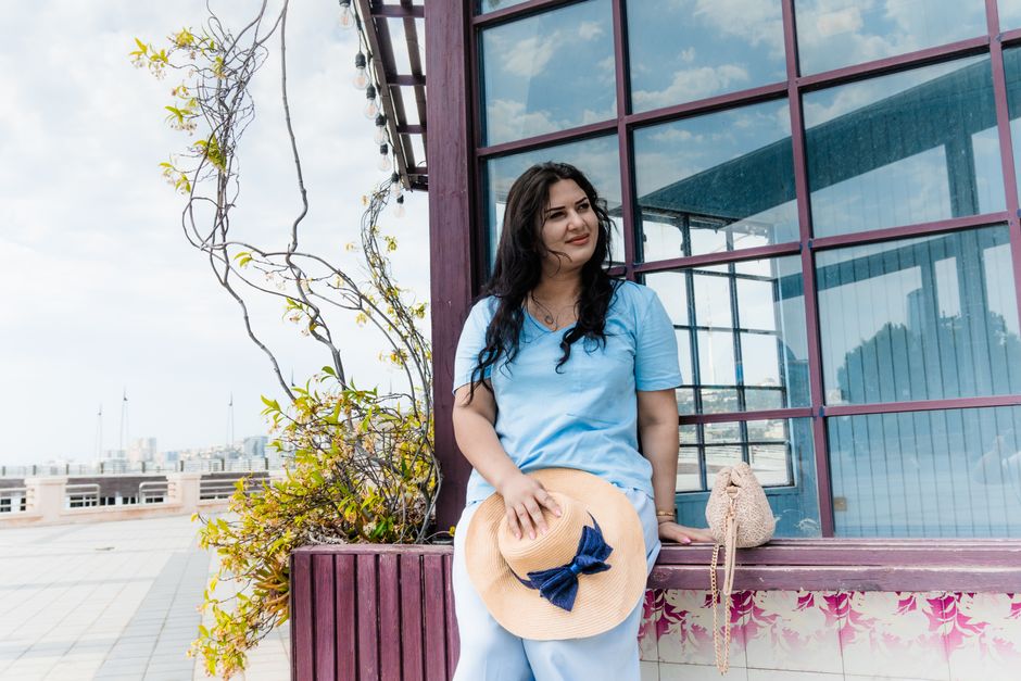 Caucasian woman enjoying a sunny day by the Baku waterfront, holding a straw hat.