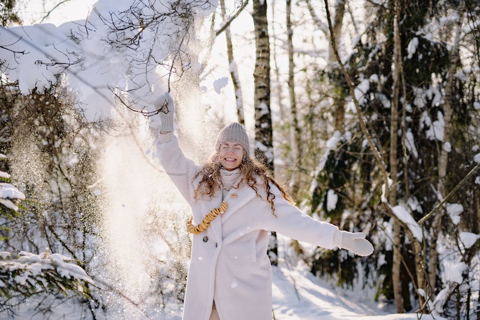 A woman joyfully plays with snow in a winter forest scene, showcasing natural beauty.